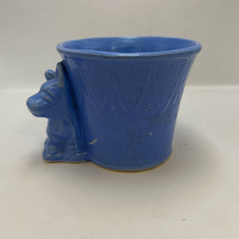 vintage blue ceramic dog planter with artificial flowers.