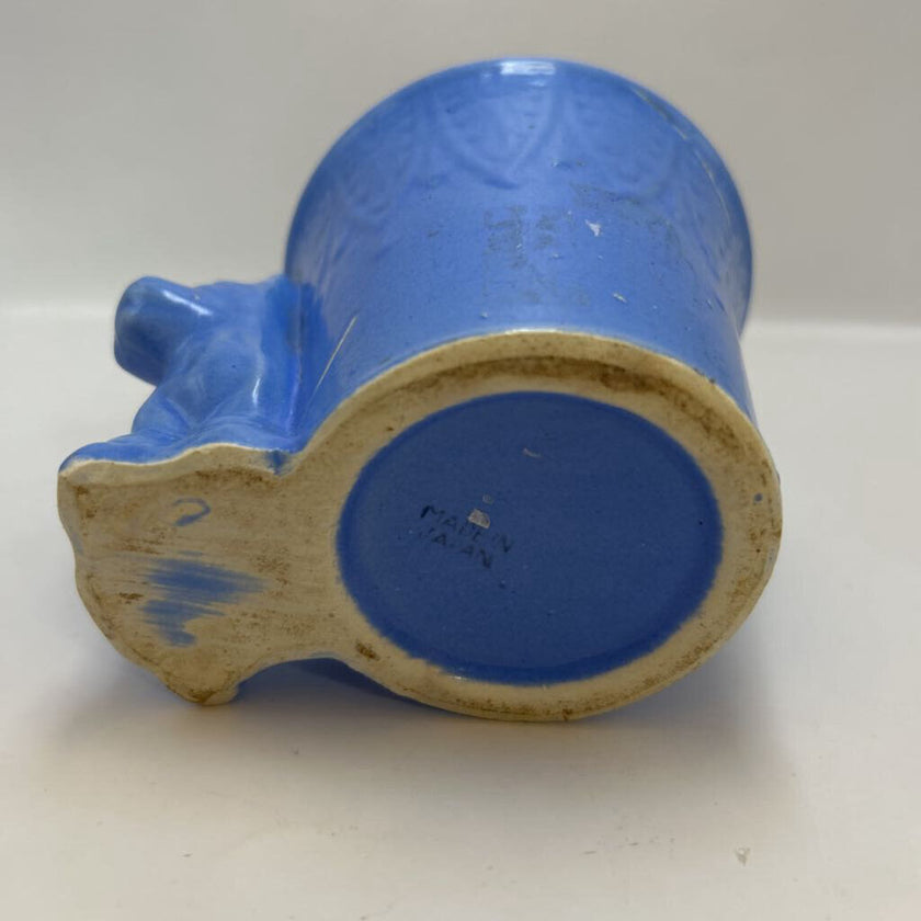 vintage blue ceramic dog planter with artificial flowers.